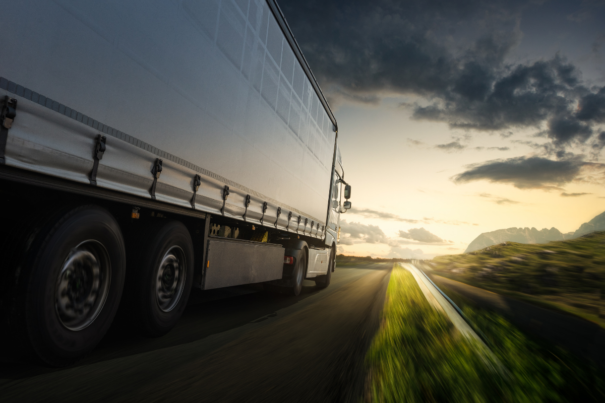 Truck driving on a highway at sundown representing cross-border logistics and international transport