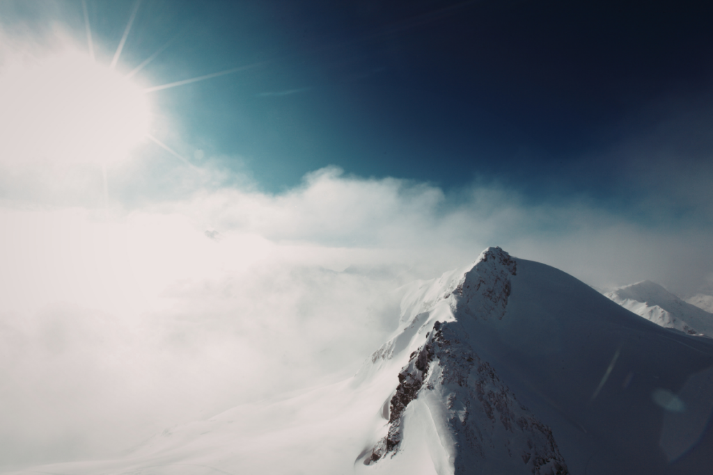Snow-covered mountain peak rising above the clouds, symbolizing ambition, achievement, and reaching new heights.