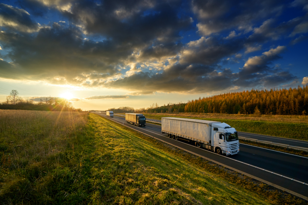 Trucks driving at sunrise, representing Professional Logistics International SA’s reliable road freight solutions.